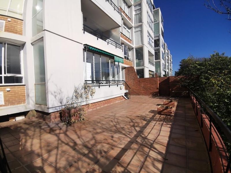 Spacious outdoor patio area featuring tiled flooring, metal railings, and a retractable awning, offering a functional space for outdoor living.