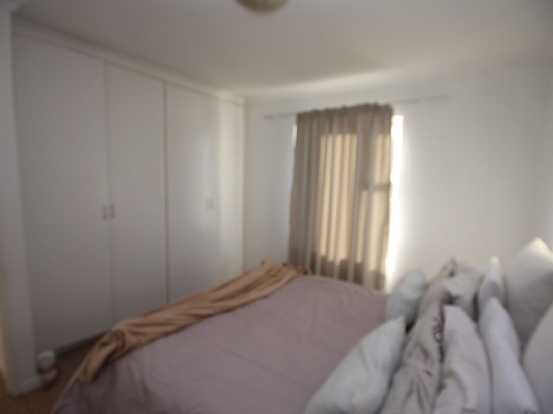 A bedroom featuring built-in cupboards and a window with curtains.