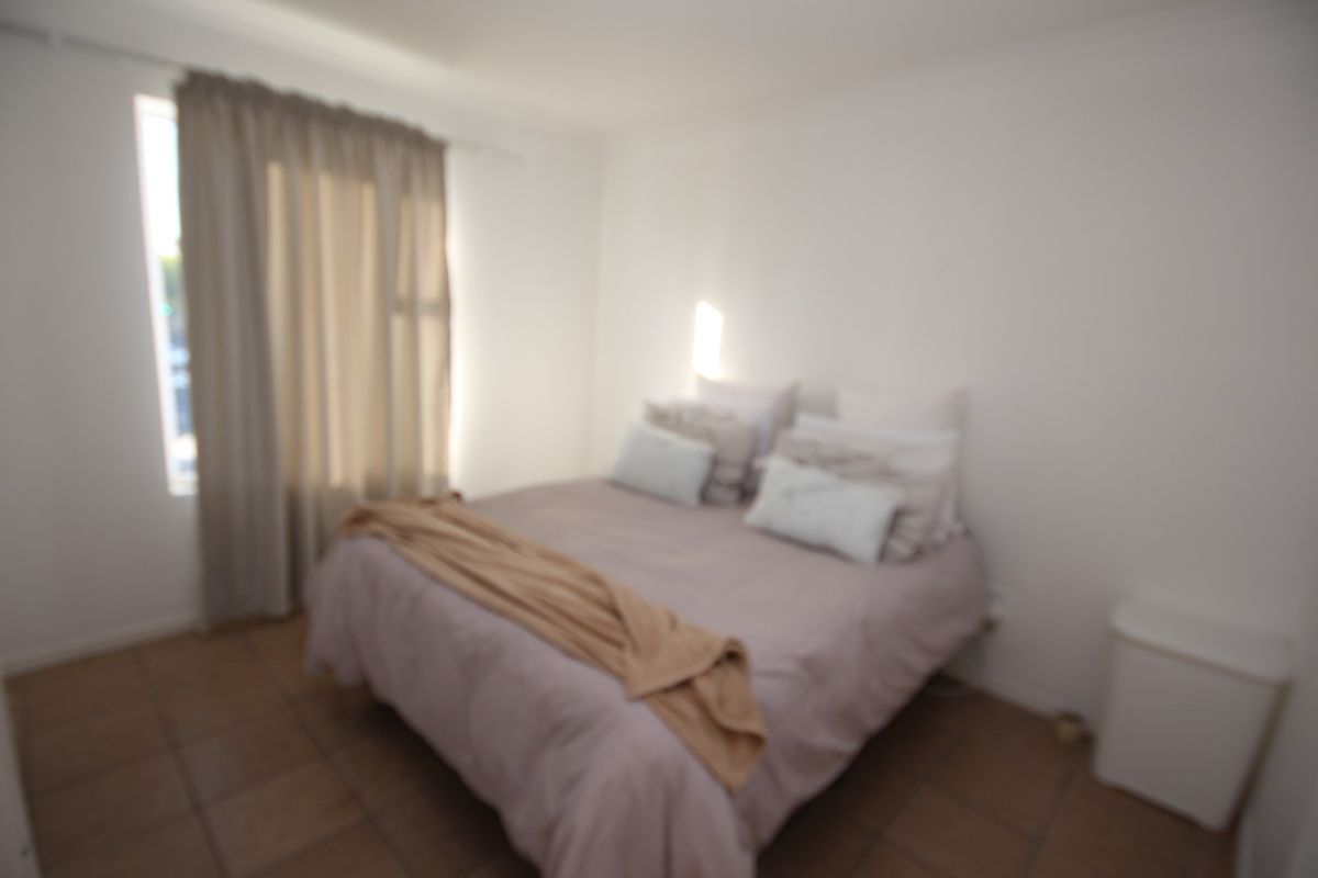 A bedroom featuring tiled flooring and window treatments.