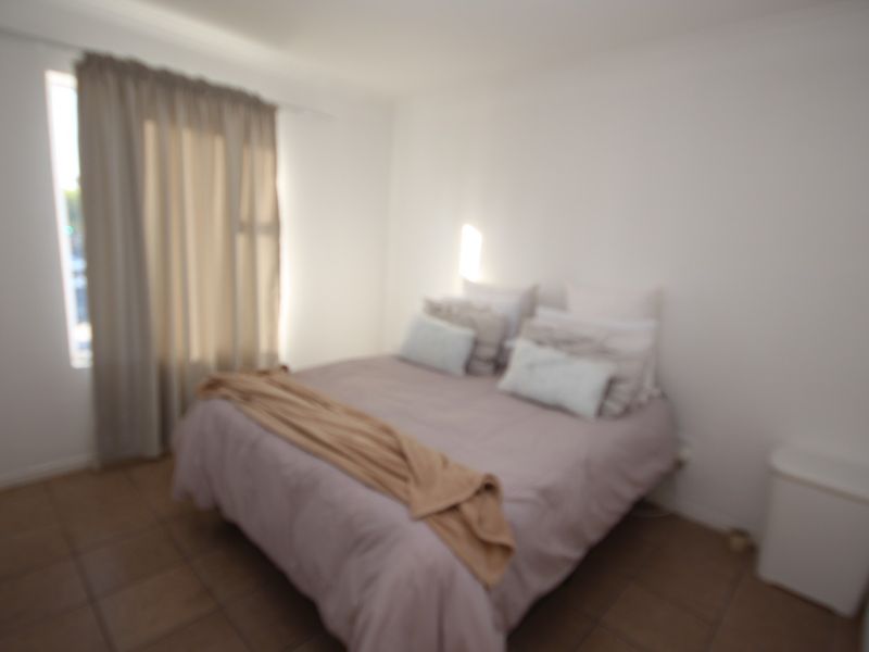 A bedroom featuring tiled flooring and window treatments.