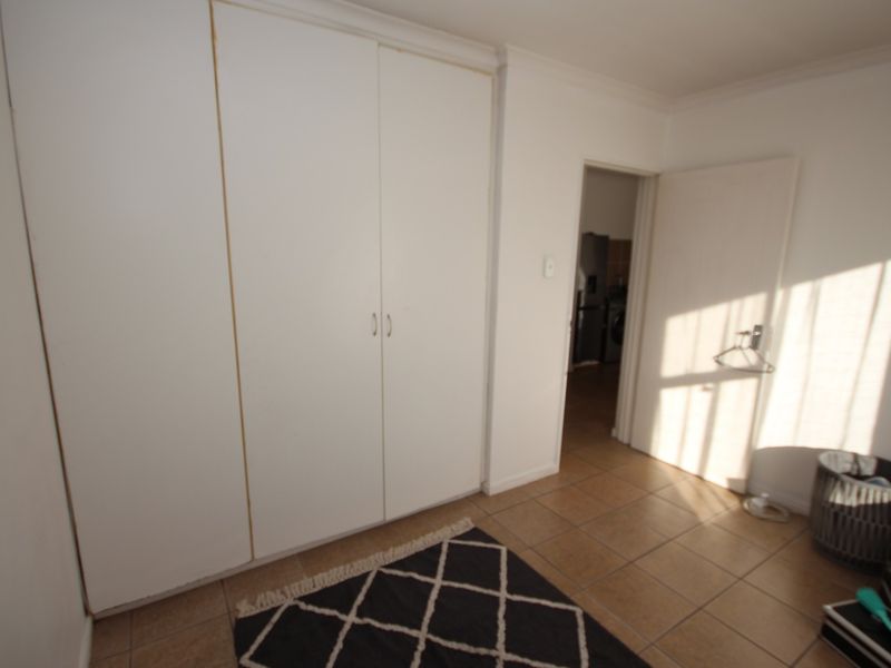 A bedroom featuring built-in cupboards and tiled flooring, with a doorway leading to an adjacent space.