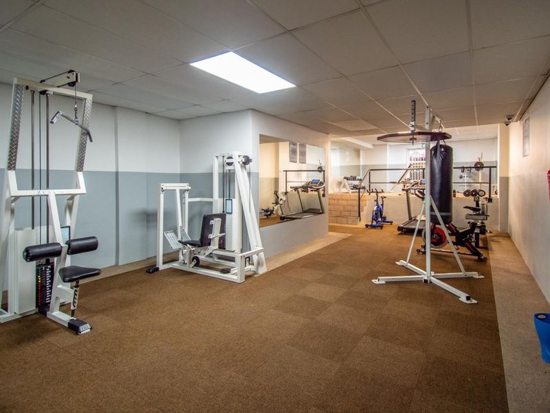 A functional residential gym space featuring a drop ceiling, recessed lighting, and a mirrored wall, providing a dedicated area for fitness activities.