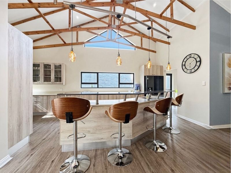 Modern kitchen featuring a large island, light wood-look cabinetry, and striking exposed timber roof trusses with high vaulted ceilings.
