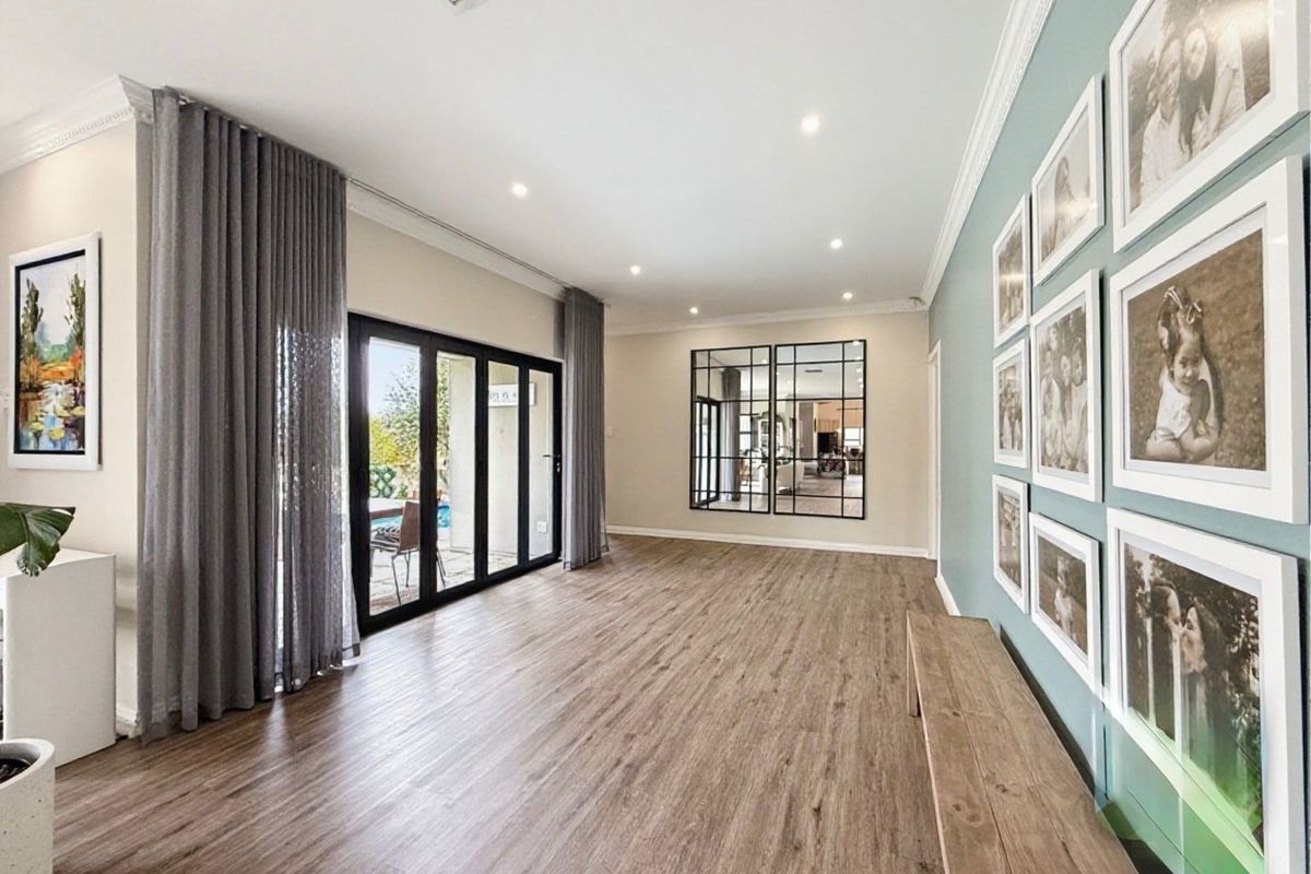 Spacious living area featuring modern laminate flooring, recessed downlights, and bi-fold glass doors providing seamless access to the outdoor patio area.