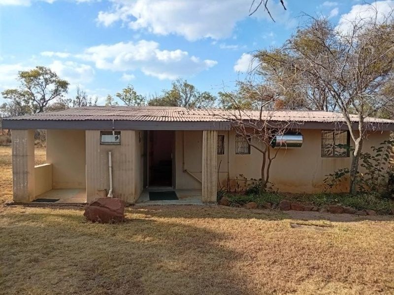 Front elevation of a rural farm dwelling featuring a corrugated metal roof, covered porch area, and external geyser unit.