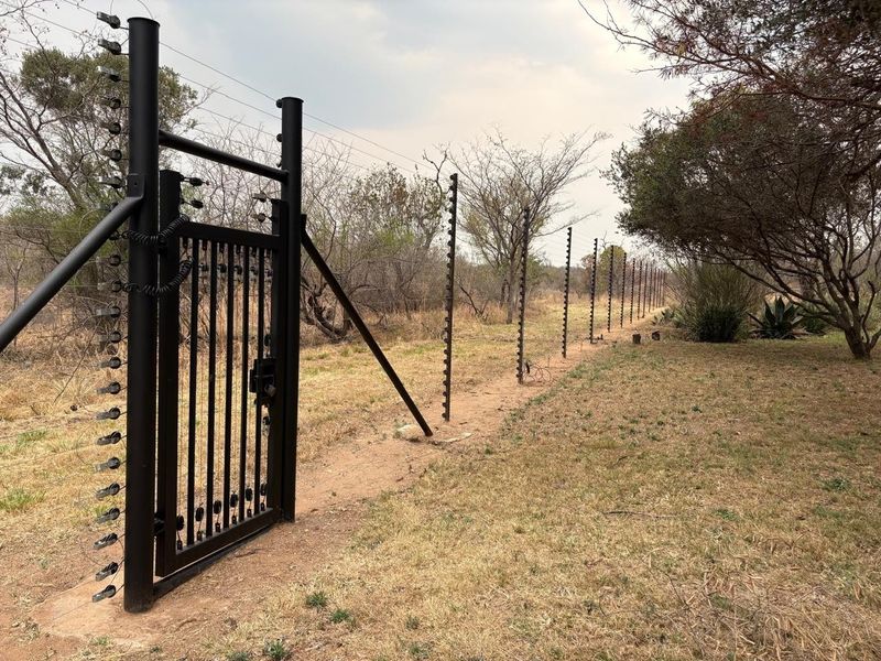 A secure perimeter boundary featuring a black metal gate and extensive electric fencing installed along the property line.