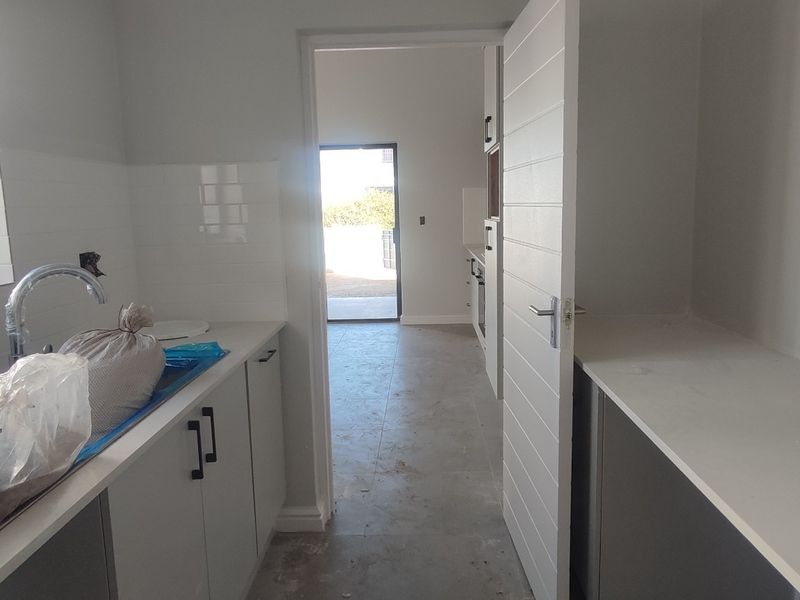 A functional scullery area featuring built-in cabinetry, stone countertops, and a stainless steel sink, currently in the final stages of completion.