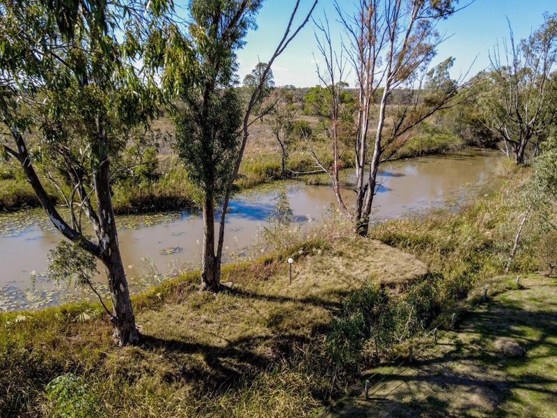 An aerial view of a natural river flowing through the farm property, surrounded by native trees and established vegetation.