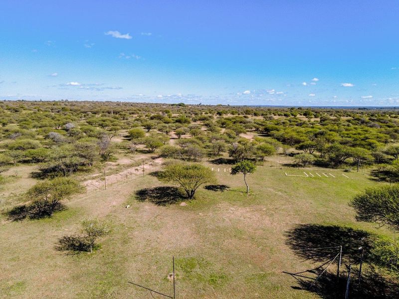 An aerial view of the expansive farm landscape featuring natural vegetation and perimeter fencing.