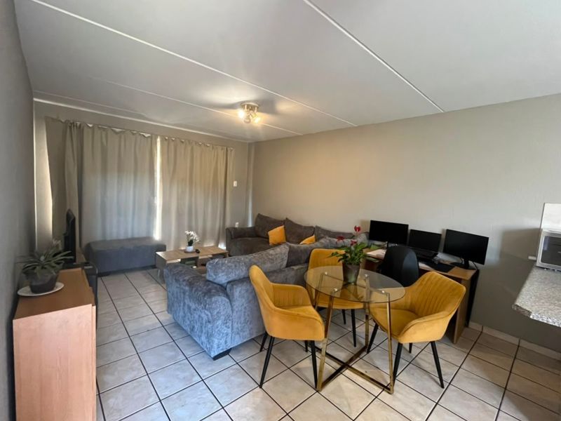 Open-plan living and dining area featuring tiled flooring and a functional kitchen corner, providing a versatile space for daily living.