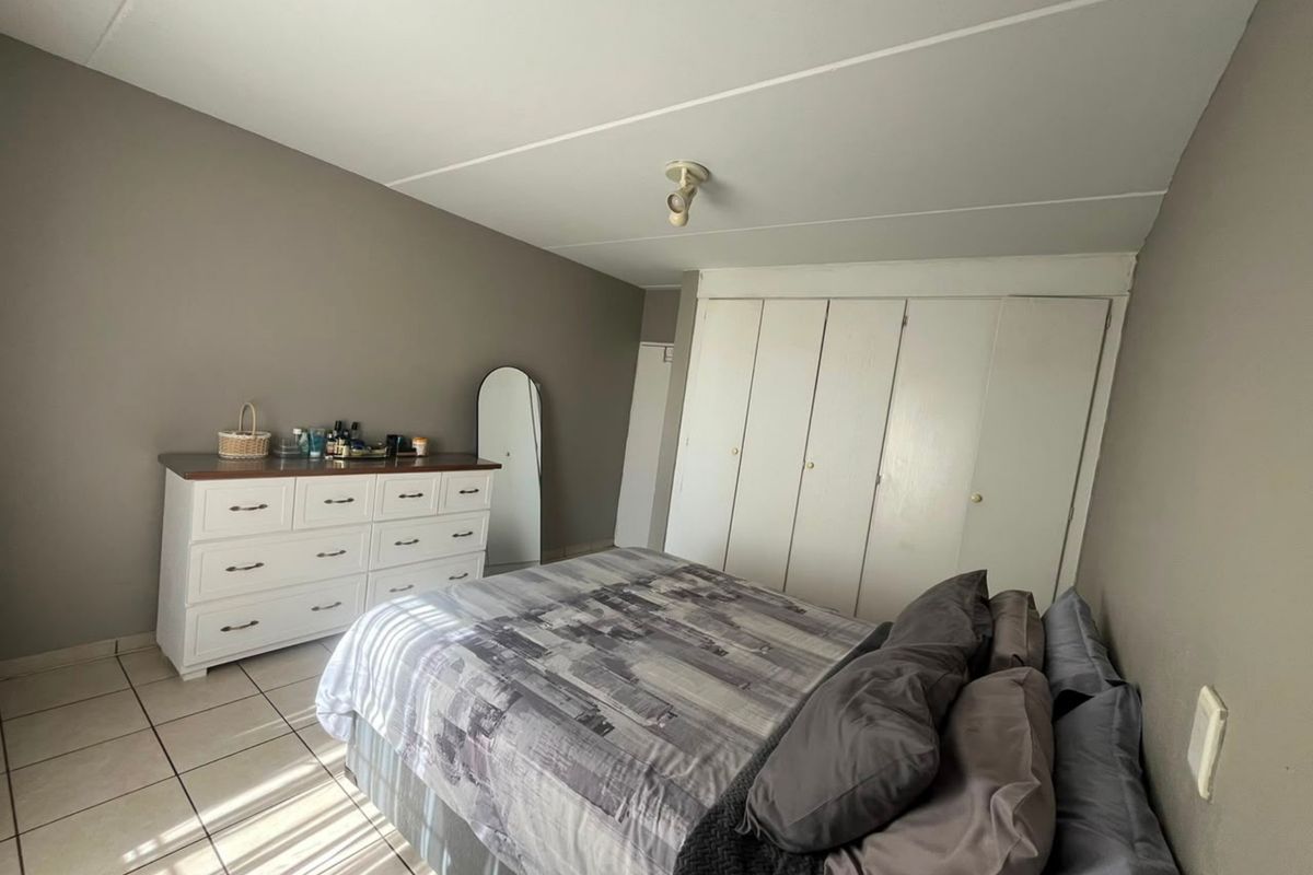 A bedroom featuring tiled flooring and built-in cupboards, providing functional storage space within the apartment.