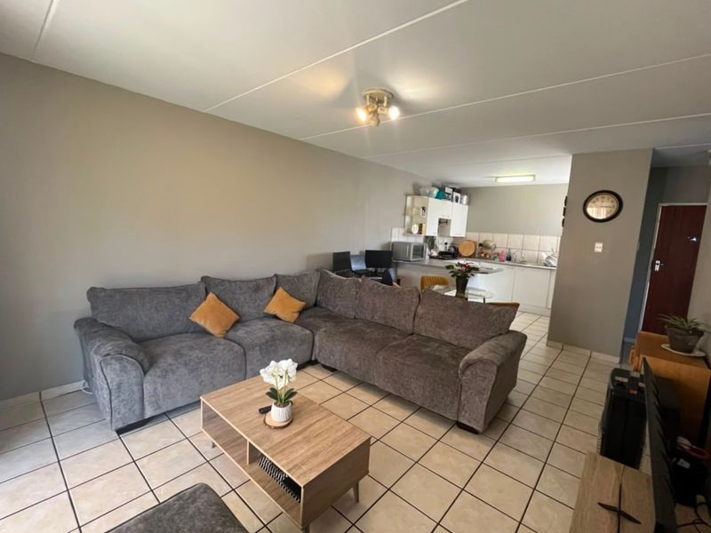 Open-plan living area featuring tiled flooring and a functional kitchen space with built-in cabinetry and sink.