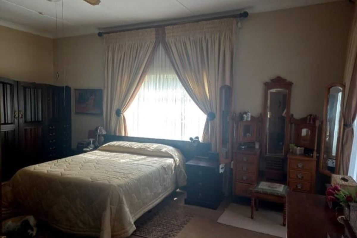 A spacious bedroom featuring a ceiling fan and large windows with curtain rods, offering a functional layout ready for modern updates.