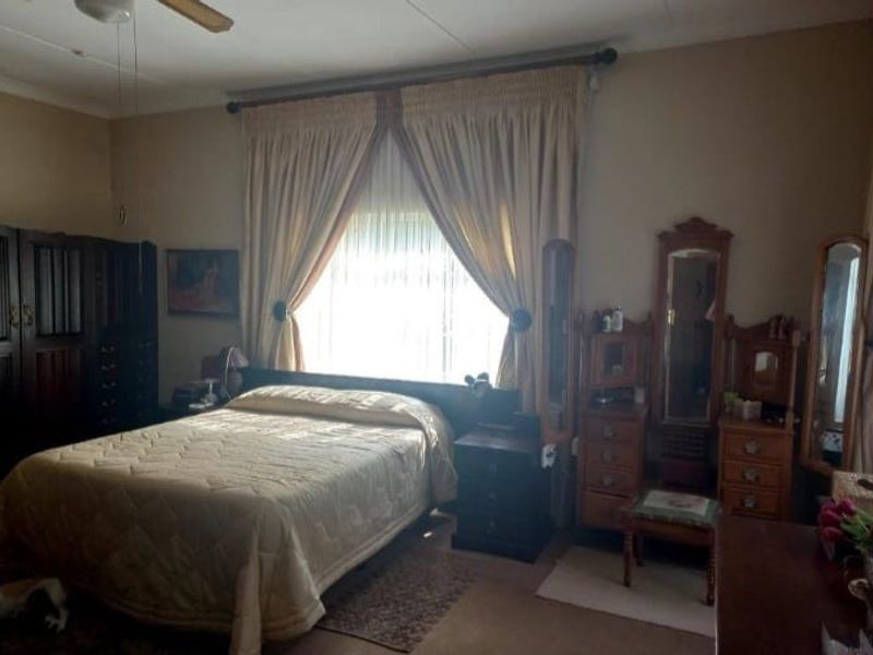 A spacious bedroom featuring a ceiling fan and large windows with curtain rods, offering a functional layout ready for modern updates.