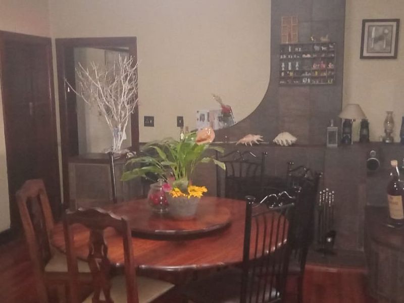 A dining room featuring hardwood flooring and a tiled fireplace surround, offering a traditional layout with direct access to adjacent living spaces.