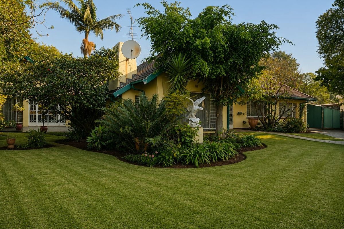 A well-maintained rear garden featuring a lush lawn, mature trees, and a paved walkway leading to the rear facade of the house.