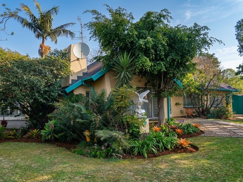 Front view of a residential house featuring a tiled roof, satellite dish, and a well-maintained landscaped garden with a paved walkway.
