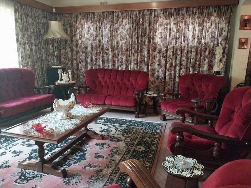 A traditional living room featuring timber ceiling detailing and full-length window curtains, offering a classic foundation for modern interior updates.