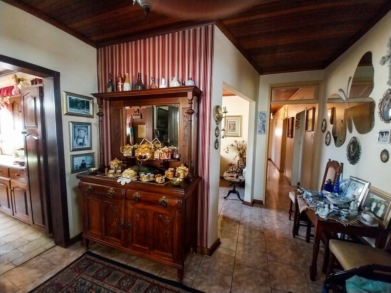 An entry foyer featuring a timber-paneled ceiling, tiled flooring, and a decorative wallpaper feature wall, providing access to adjacent living areas.