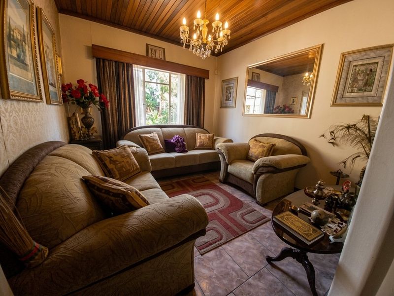 A cozy living room featuring a warm timber-clad ceiling, tiled flooring, and a classic chandelier, creating a traditional and inviting atmosphere.