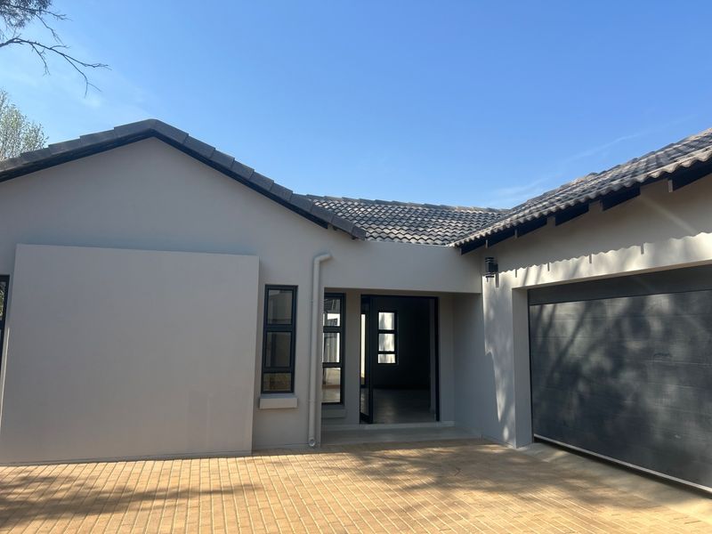 Front elevation of a modern house featuring a paved driveway, tiled roof, and integrated garage.