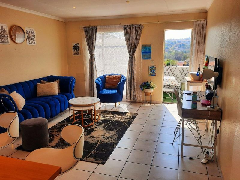 A bright living room featuring tiled flooring, recessed lighting, and direct access to a private balcony with scenic views.