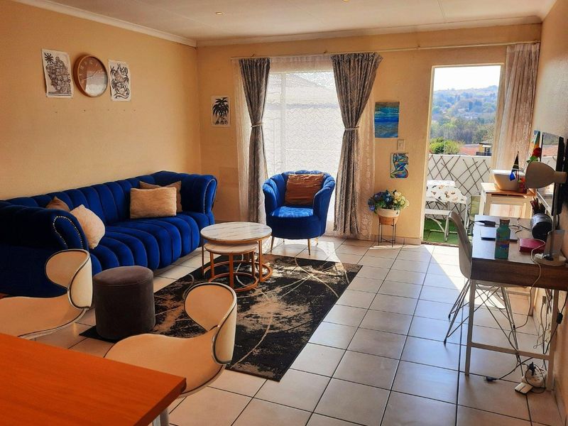 A bright living room featuring tiled flooring, recessed lighting, and direct access to an outdoor balcony area with scenic views.