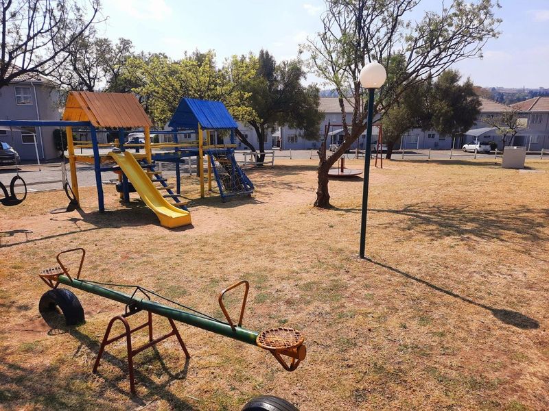 Communal garden area featuring a playground with slides and climbing structures, set within an apartment complex.