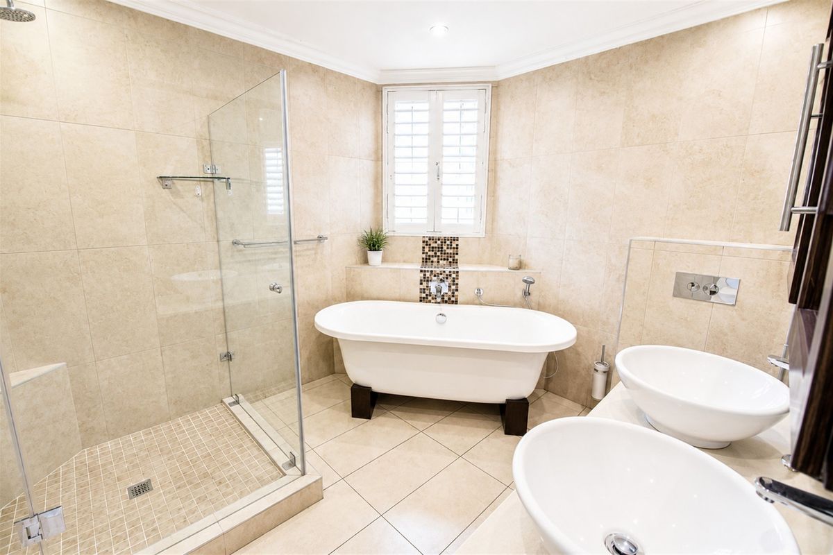 A well-appointed modern bathroom featuring a freestanding bathtub, a glass-enclosed shower, and a double vanity with contemporary basin sinks.