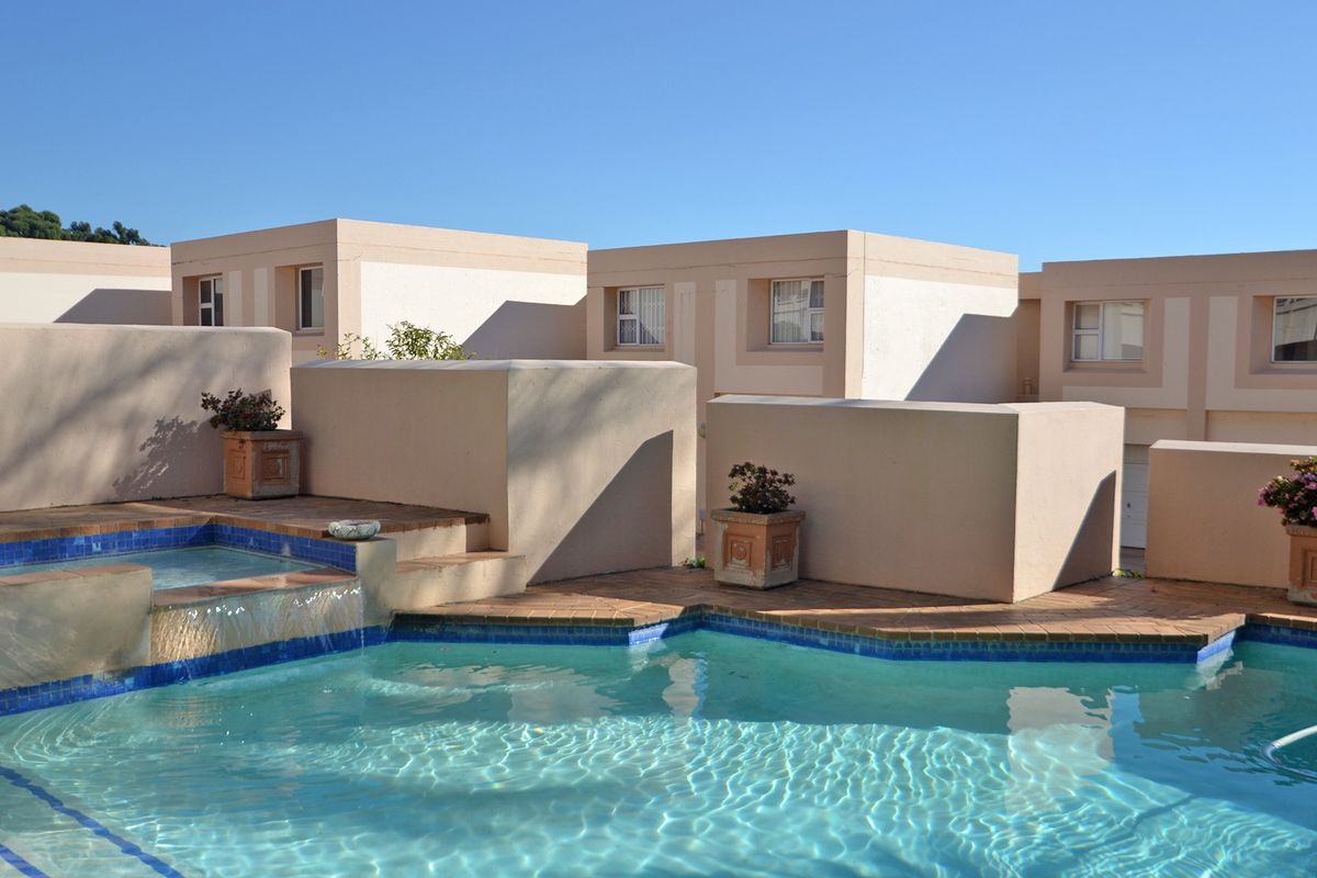 Outdoor pool area featuring a built-in water feature and tiled surround, set against the exterior facade of the townhouse complex.