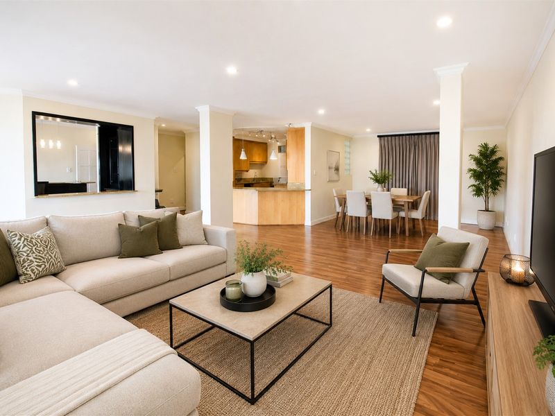 Spacious open-plan living and dining area featuring timber flooring, recessed lighting, and a functional kitchen with stone countertops and ample cabinetry.