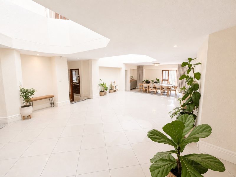 Spacious open-plan living and dining area featuring bright tiled flooring, recessed lighting, and large architectural skylights providing ample natural light.