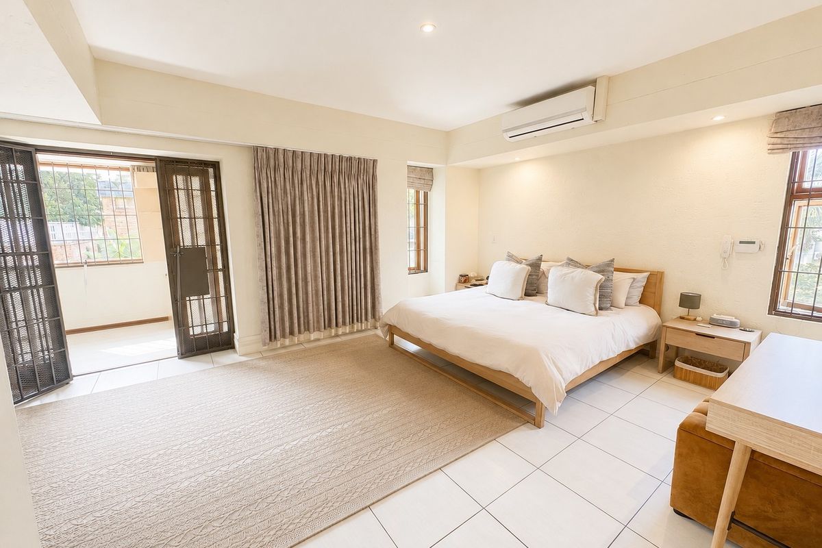 Spacious bedroom featuring tiled flooring, recessed lighting, a split-system air conditioner, and direct access to an outdoor patio area through a security gate.