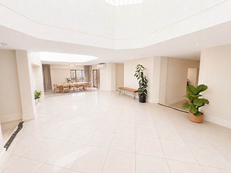Spacious open-plan living area featuring large skylights, neutral tiled flooring, and recessed lighting, creating a bright and airy atmosphere.