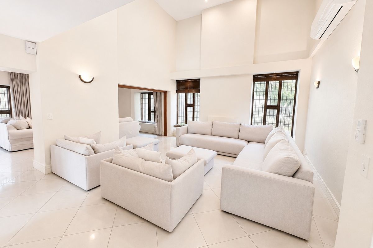 Spacious living room featuring high vaulted ceilings, large windows, tiled flooring, and a wall-mounted air conditioning unit in a bright, neutral setting.