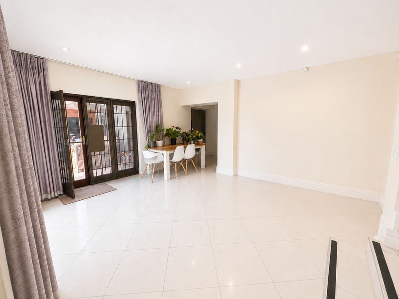 Spacious living area featuring neutral walls, polished tiled flooring, recessed lighting, and direct access to the outdoor area through a secure glass door.