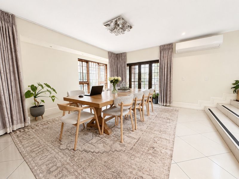 A bright and spacious dining room featuring tiled flooring, a split-system air conditioner, and large windows with access to the exterior via french doors.
