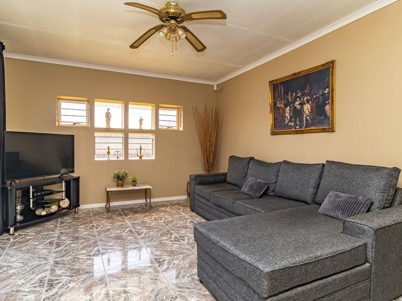 A living room featuring tiled flooring, a ceiling fan, and louver windows, providing a functional space for relaxation.
