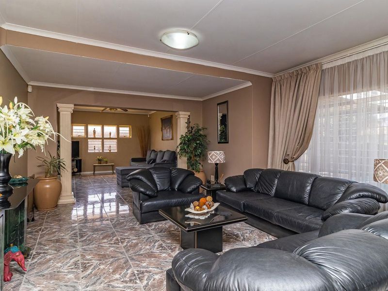 Spacious living area featuring tiled flooring, decorative columns, and natural light through large windows, offering a comfortable and open layout.