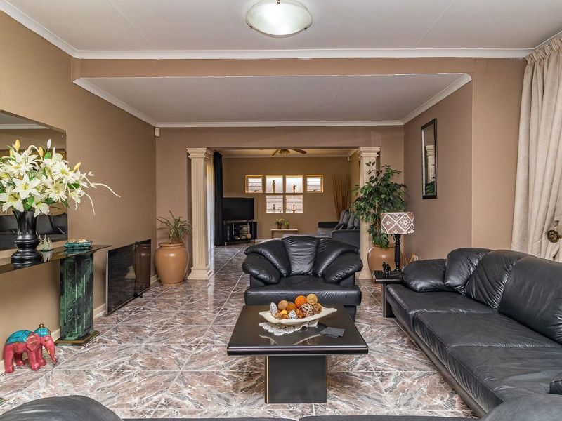 Spacious living area featuring tiled flooring, decorative columns, and coved cornicing, offering a versatile layout with an adjoining secondary living space.