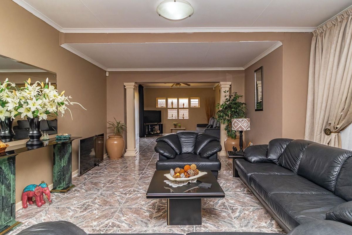 Spacious living area featuring tiled flooring, decorative columns, and coved cornicing, offering a versatile layout with an adjoining secondary living space.
