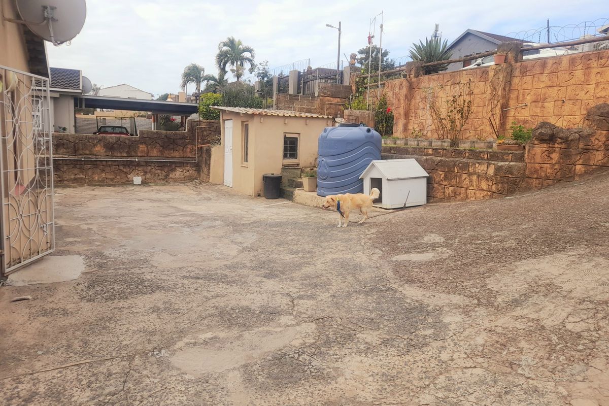 Rear exterior area featuring concrete paving, a retaining wall, and a water storage tank, offering potential for landscaping or outdoor improvement.