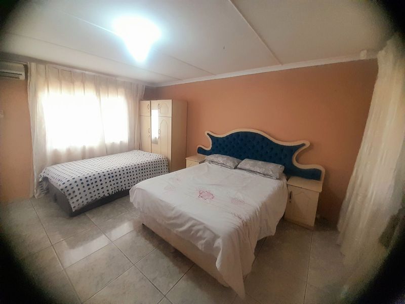 A bedroom featuring tiled flooring and an installed air conditioning unit, providing a functional space with neutral wall tones.