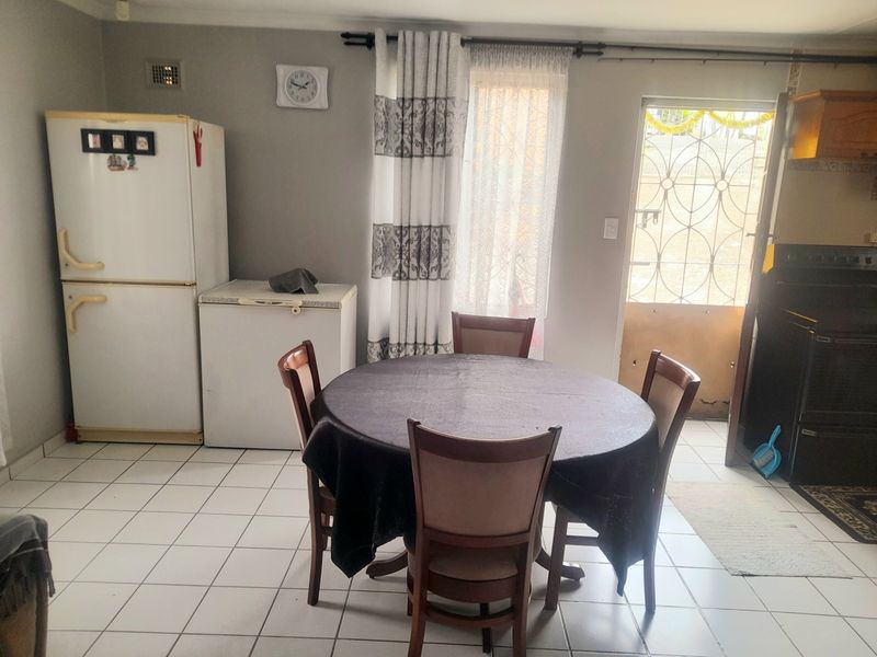 A functional kitchen area featuring tiled flooring and direct access to the exterior via a security gate.