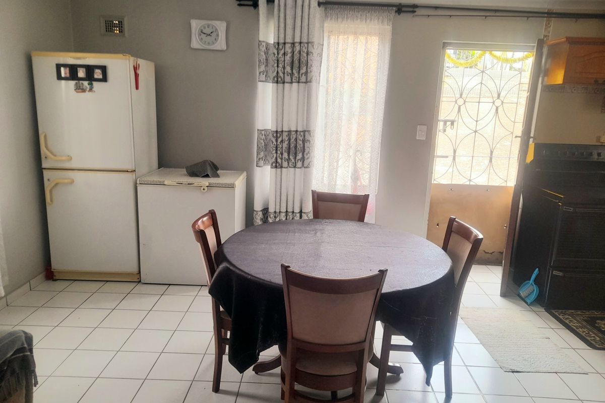 A functional kitchen area featuring tiled flooring and direct access to the exterior via a security gate.
