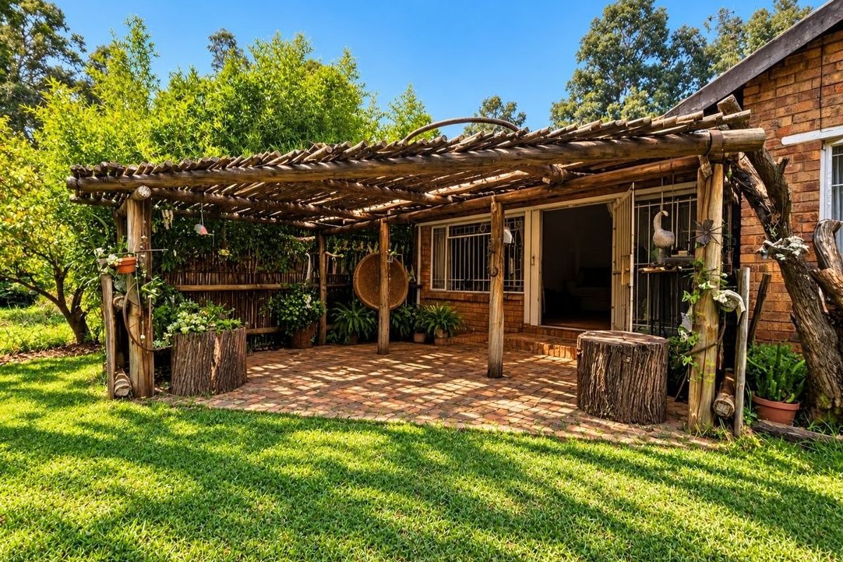 A rustic outdoor patio area featuring a timber pergola structure and brick paving, providing a shaded transition space between the garden and the home.