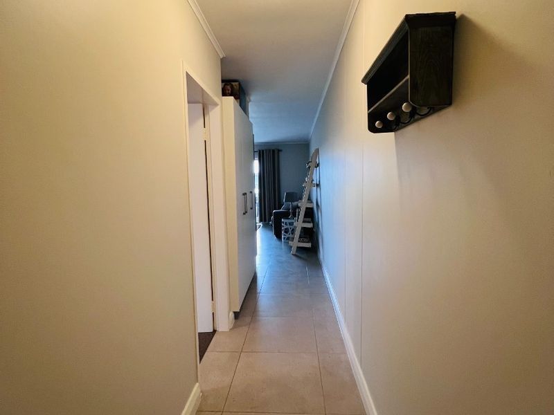 A clean, tiled hallway providing access to the living area, featuring neutral wall finishes and a central ceiling light.