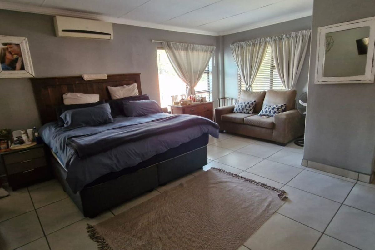 Spacious bedroom featuring tiled flooring, cove cornicing, and a wall-mounted air conditioning unit.
