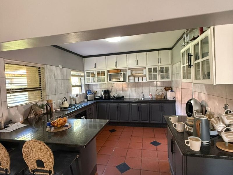 Spacious kitchen featuring dark cabinetry, granite countertops, a central island, and tiled flooring, offering a functional layout with ample storage and preparation space.