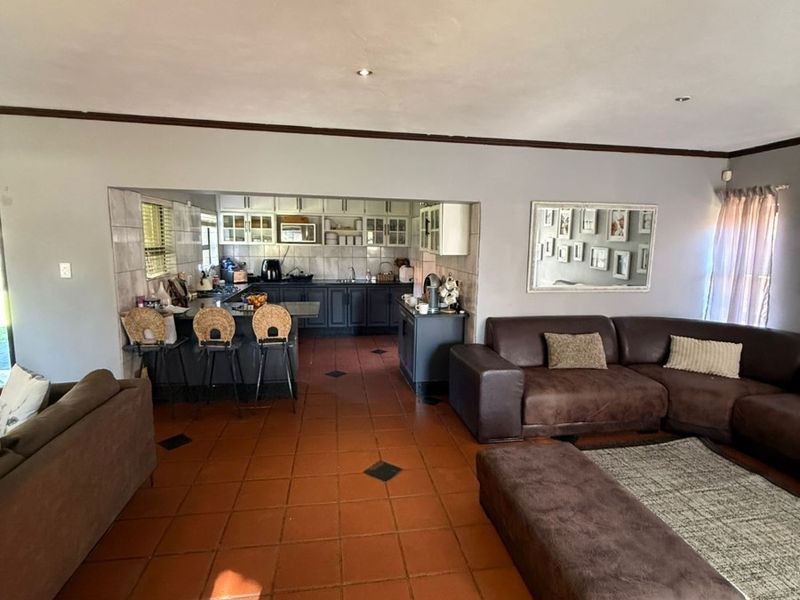Open-plan living area featuring terracotta floor tiles and a connected kitchen with dark cabinetry, providing a functional and spacious layout for family living.
